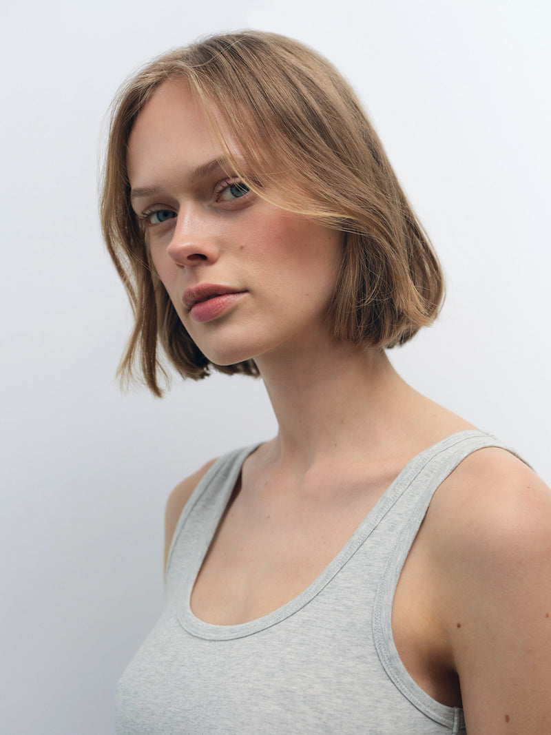 Woman wearing a light grey Organic Comfort Crop Tank, showcasing its smooth organic cotton jersey fabric and close-to-body fit.