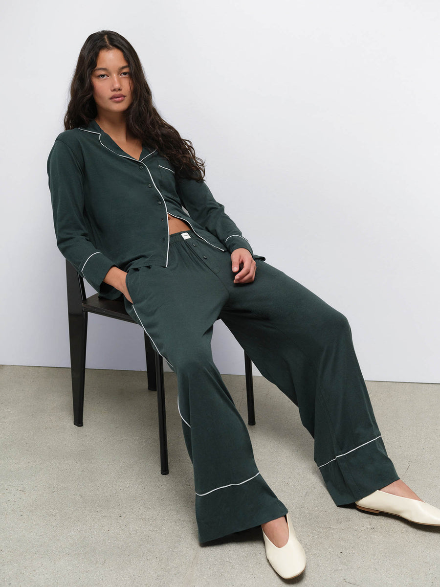 Model seated on a chair wearing the Tencel Sleep Set in Balsam with Heather Grey piping