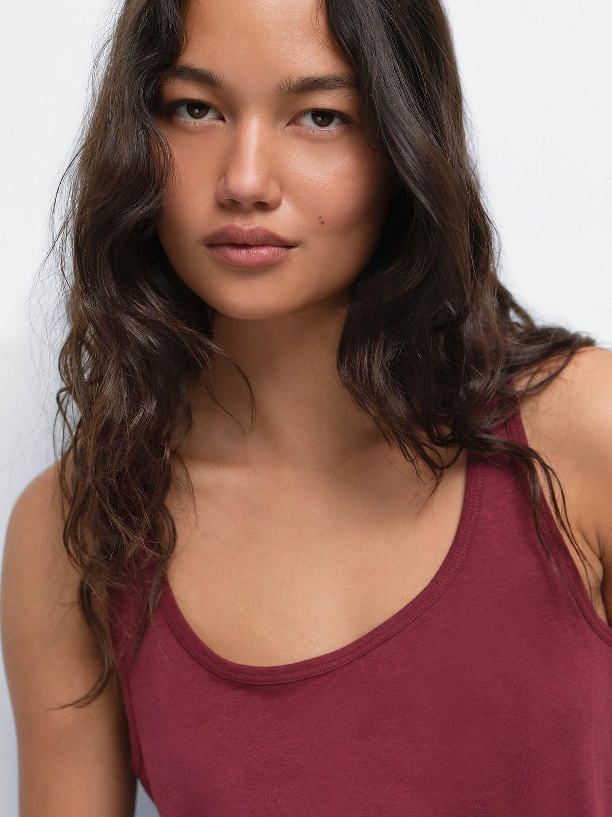 Close-up portrait of model wearing the Tencel Sleep Scoop Tank in Garnet