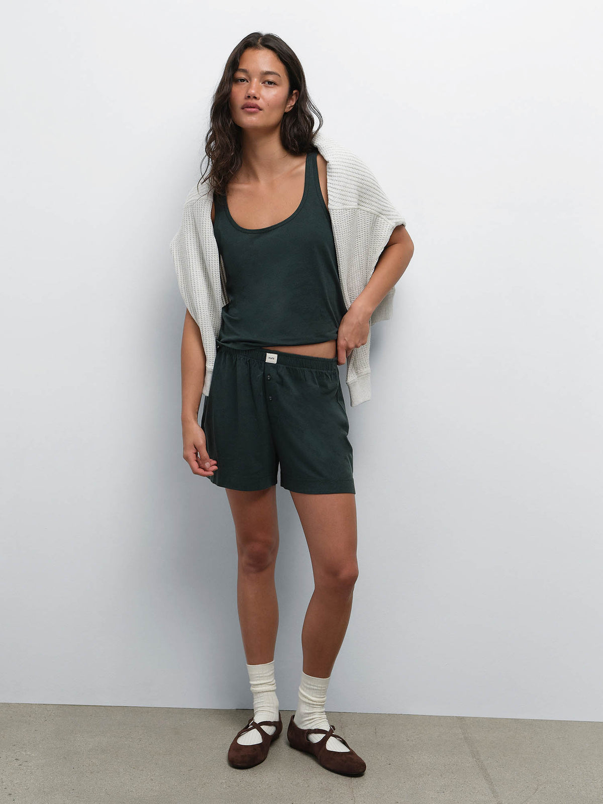 Full-length view of model with a cream cardigan over her shoulders, wearing the Tencel Sleep Scoop Tank and Boxer Short in Balsam