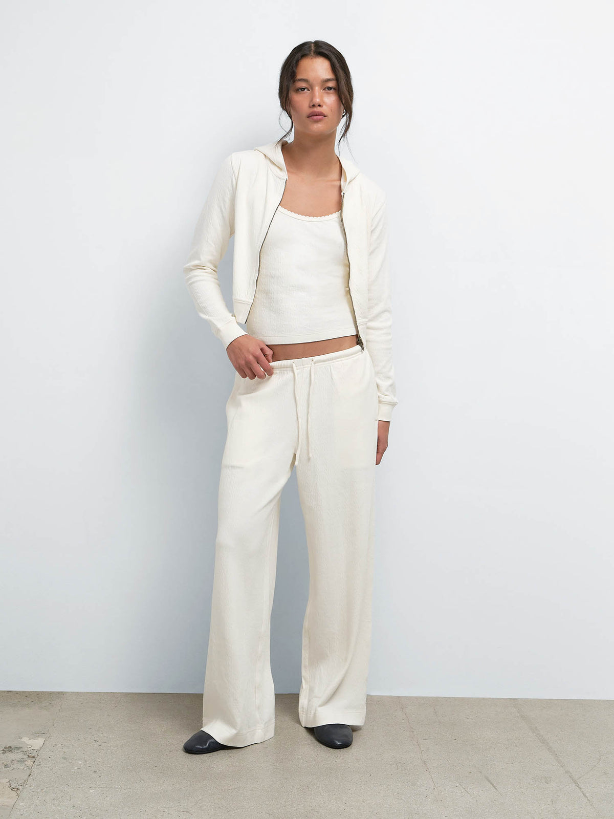 Model standing with the Organic Pointelle Shrunken Hoodie open over the matching Tank and Pant in Cream