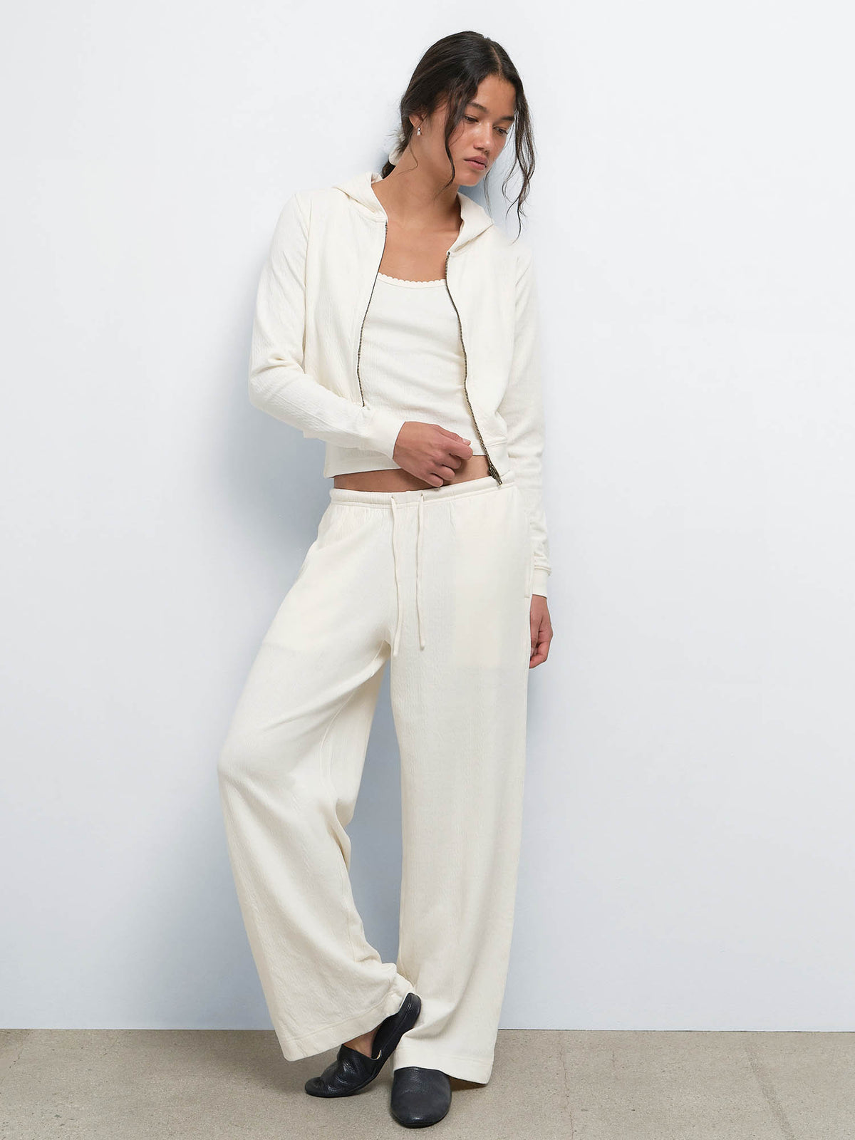 Full-length view of model in the Organic Pointelle Shrunken Hoodie, Tank and Pant in Cream with black shoes