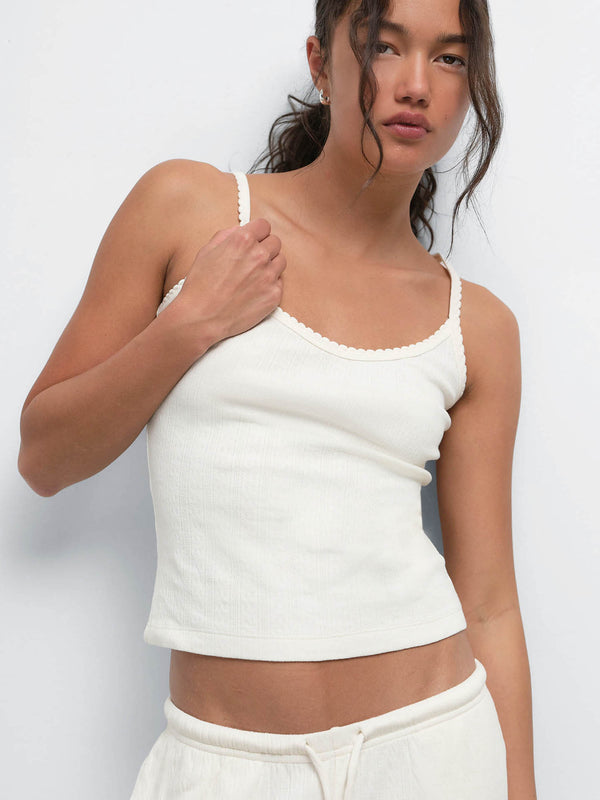 Model adjusting the strap of the Organic Pointelle Tank in Cream, worn with the matching pant