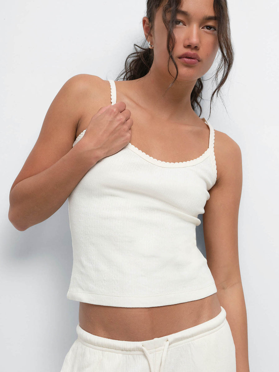Model adjusting the strap of the Organic Pointelle Tank in Cream, worn with the matching pant