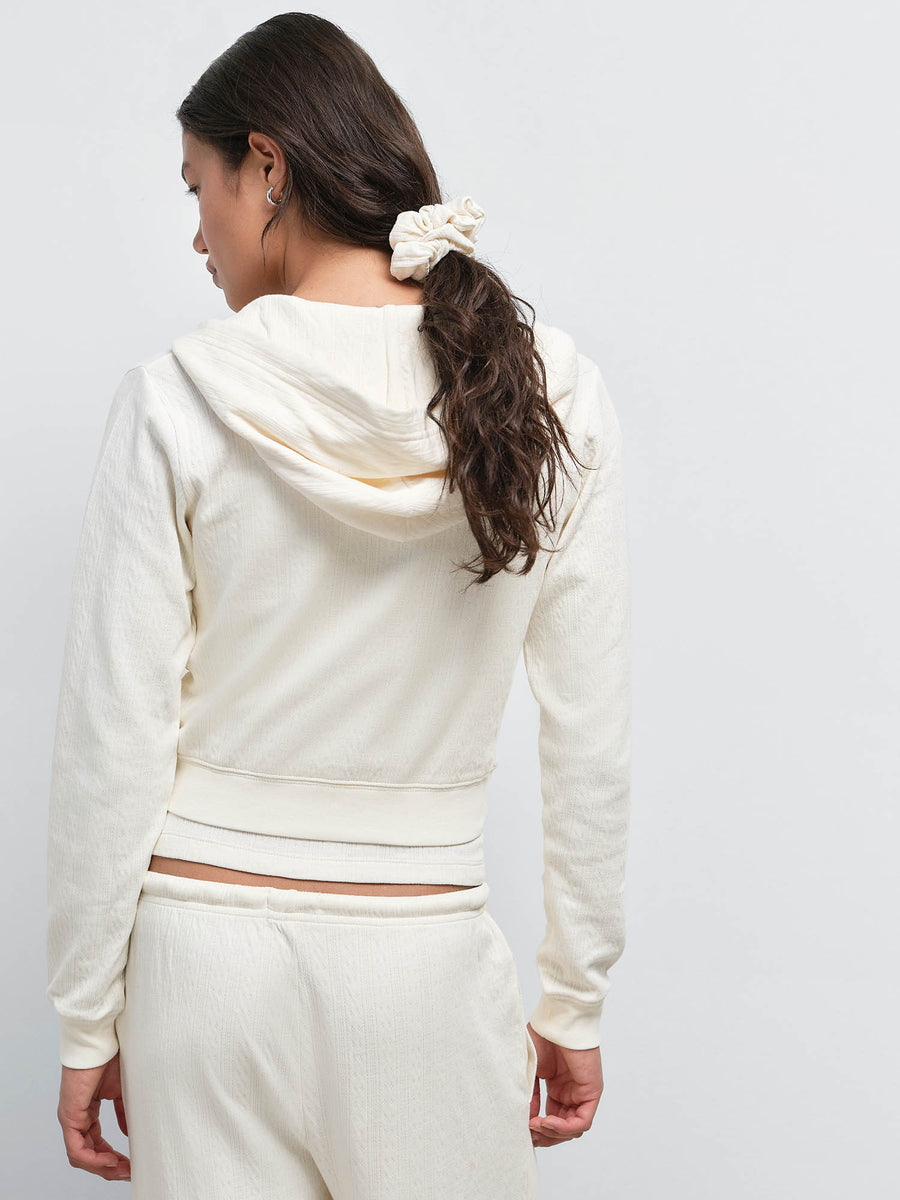 Back view of model in the Organic Pointelle Shrunken Hoodie and Pant in Cream, hair in a ponytail with a scrunchie