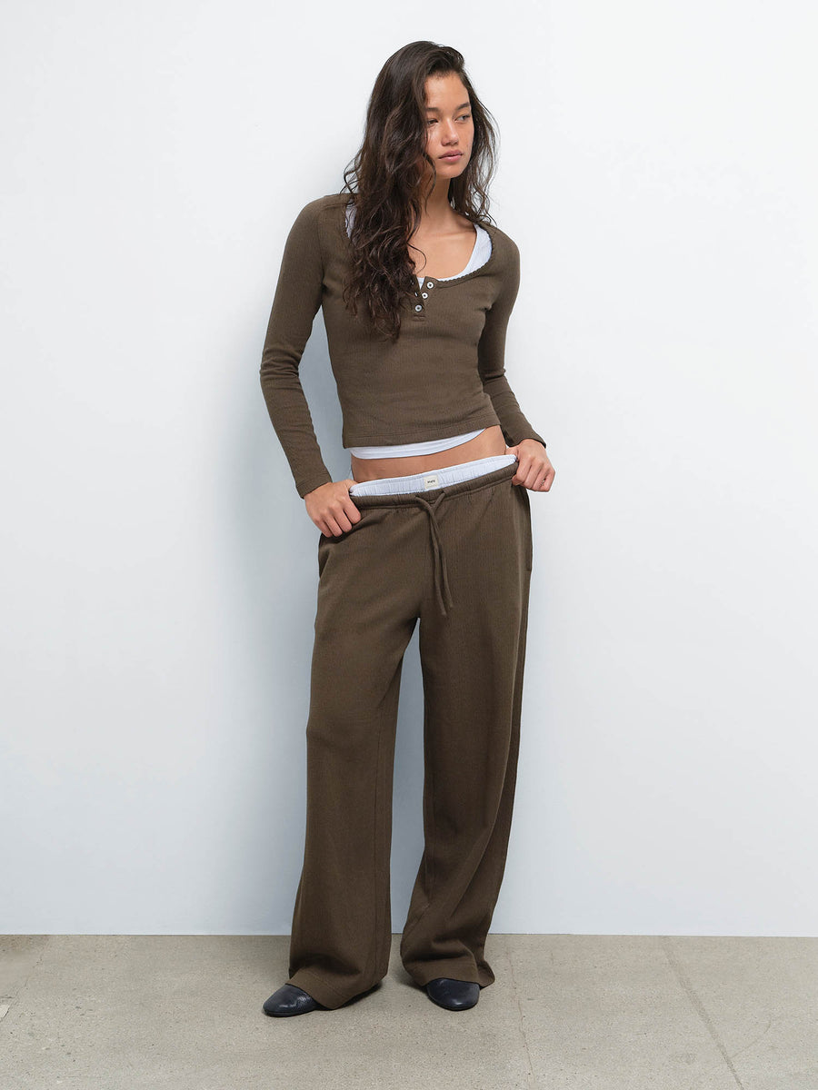 Full-length view of model with hands in pockets wearing the Organic Pointelle Henley and Pant in Mocha