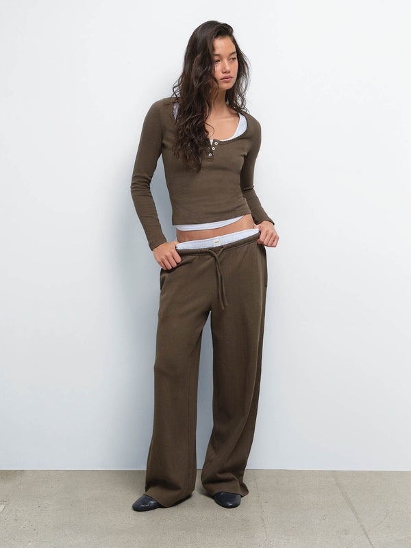 Full-length view of model with hands in pockets wearing the Organic Pointelle Henley and Pant in Mocha