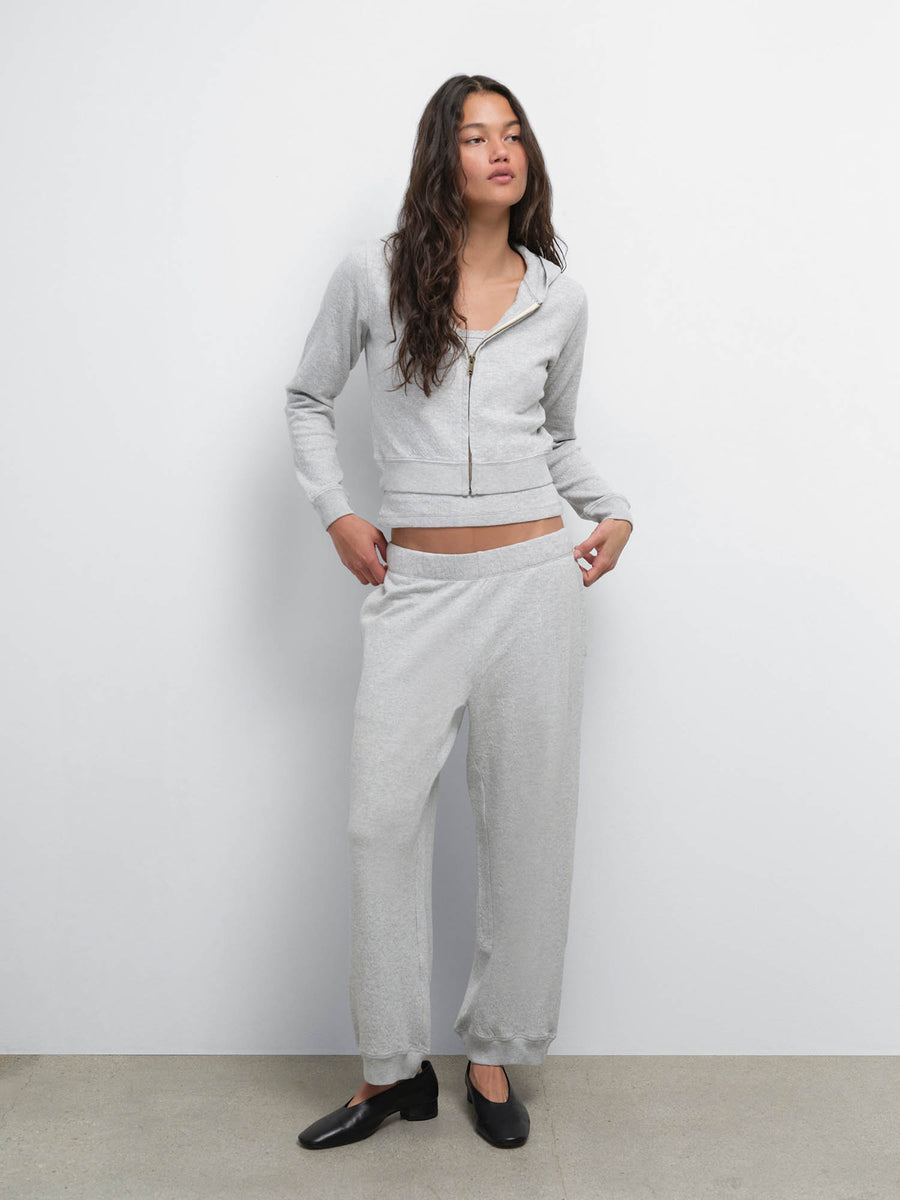 Full-length view of model with hands in pockets wearing the Organic Pointelle Shrunken Hoodie and Jogger in Heather Grey