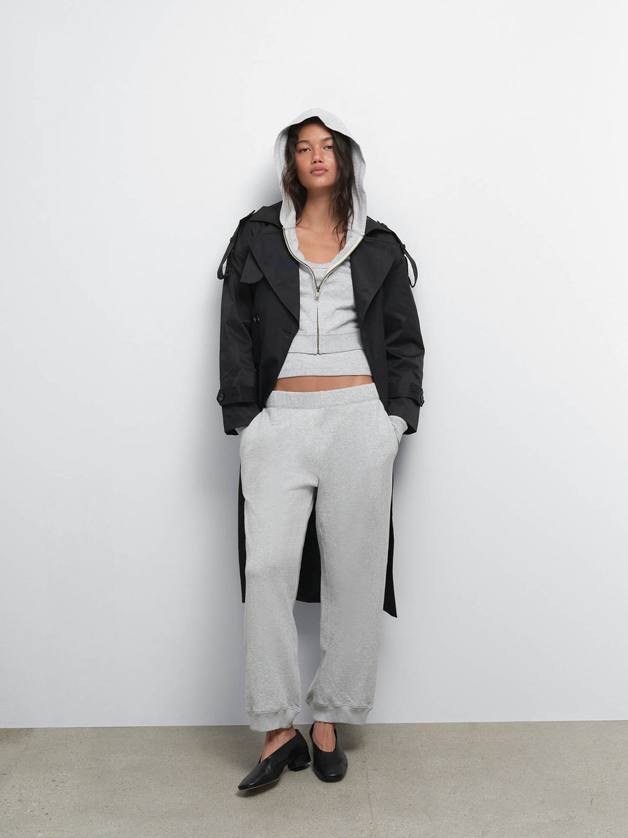 Full-length view of model in a black jacket over the Organic Pointelle Shrunken Hoodie and Jogger in Heather Grey