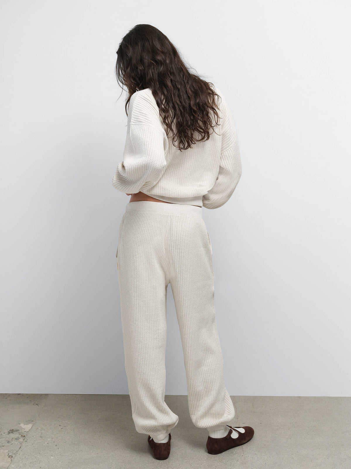 Back view of model looking over her shoulder in the Organic Waffle Crewneck Sweatshirt and Sweatpant in Oat