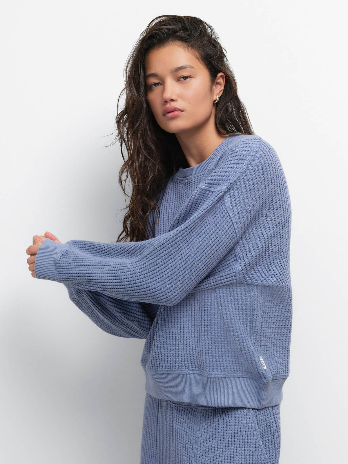 Model stretching out one arm in the Organic Waffle Crewneck Sweatshirt in Bay