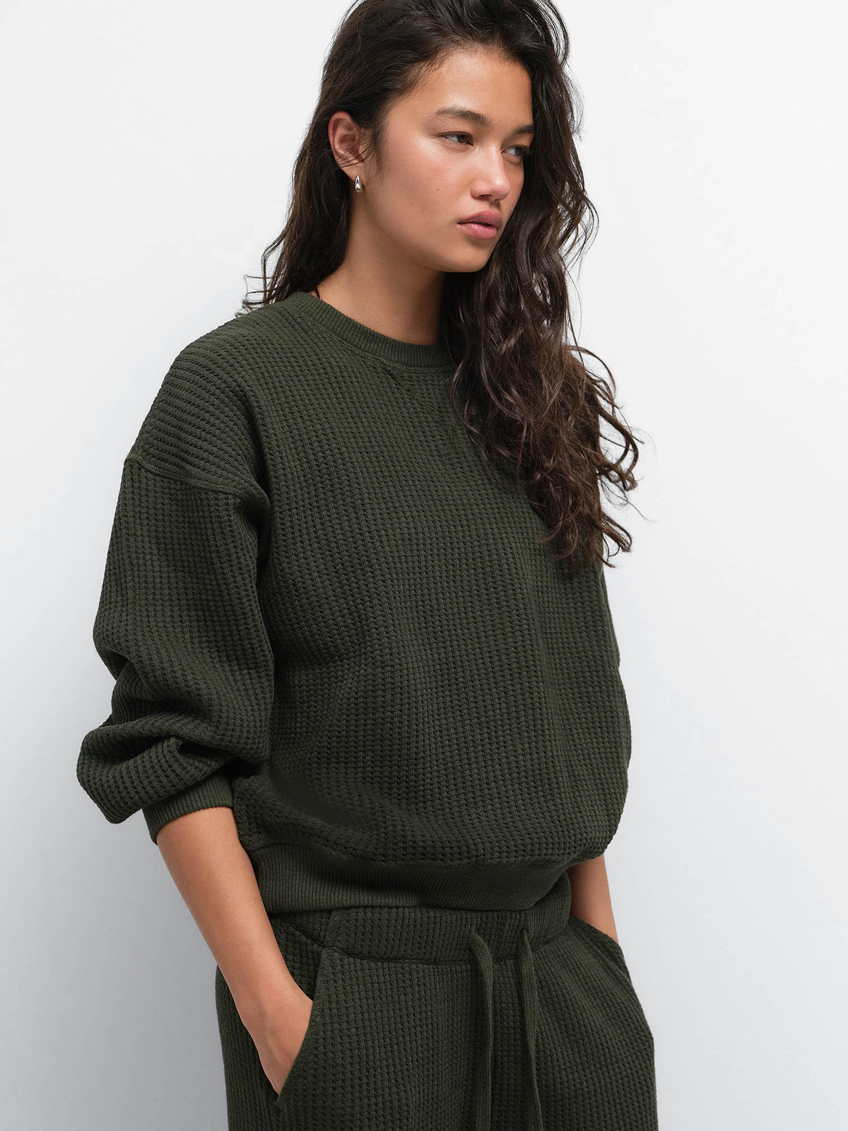 Model with hands in pockets wearing the Organic Waffle Crewneck Sweatshirt and Straight Leg Sweatpant in Heather Pine