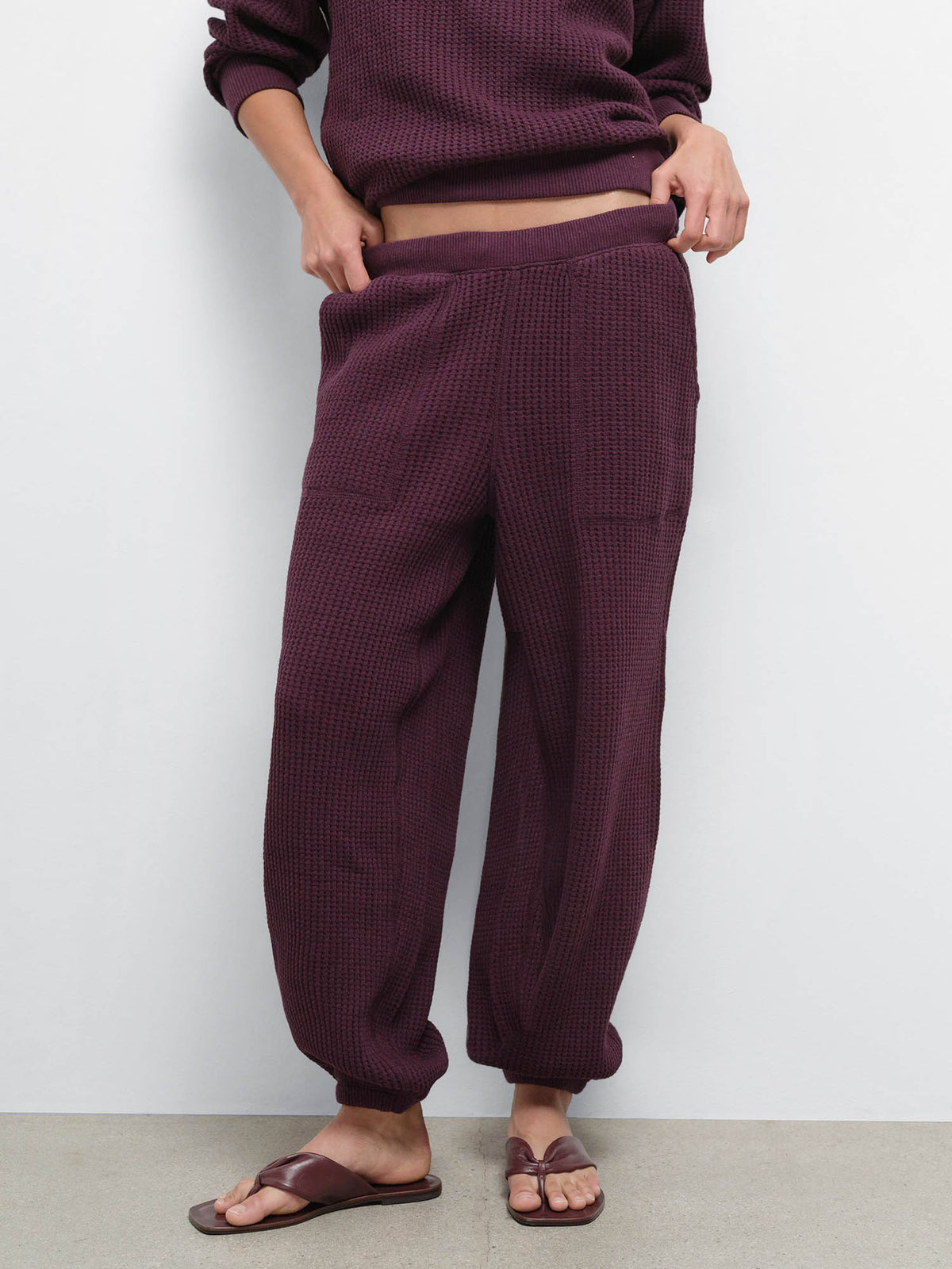 Close-up of the Organic Waffle Sweatpant in Merlot worn with brown flip-flop sandals