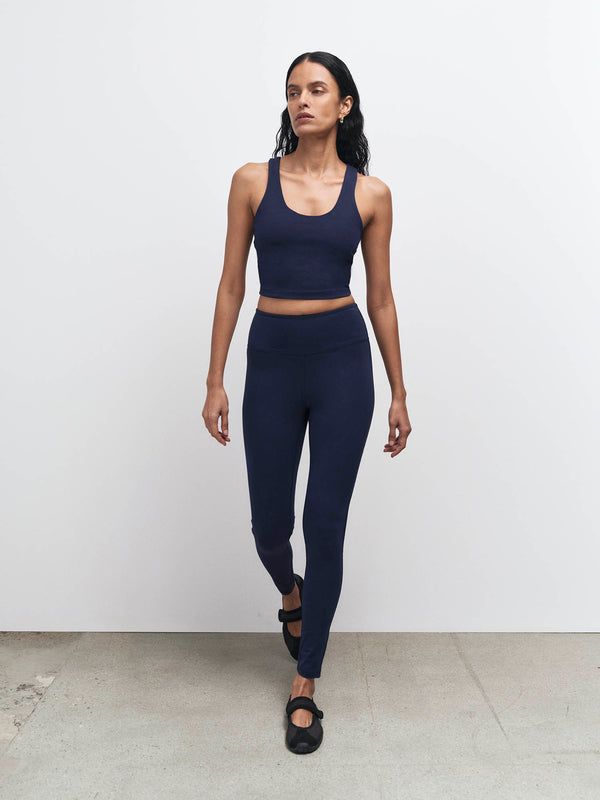 Model walking in a midnight navy organic stretch sports bra and midi leggings – MATE the Label activewear