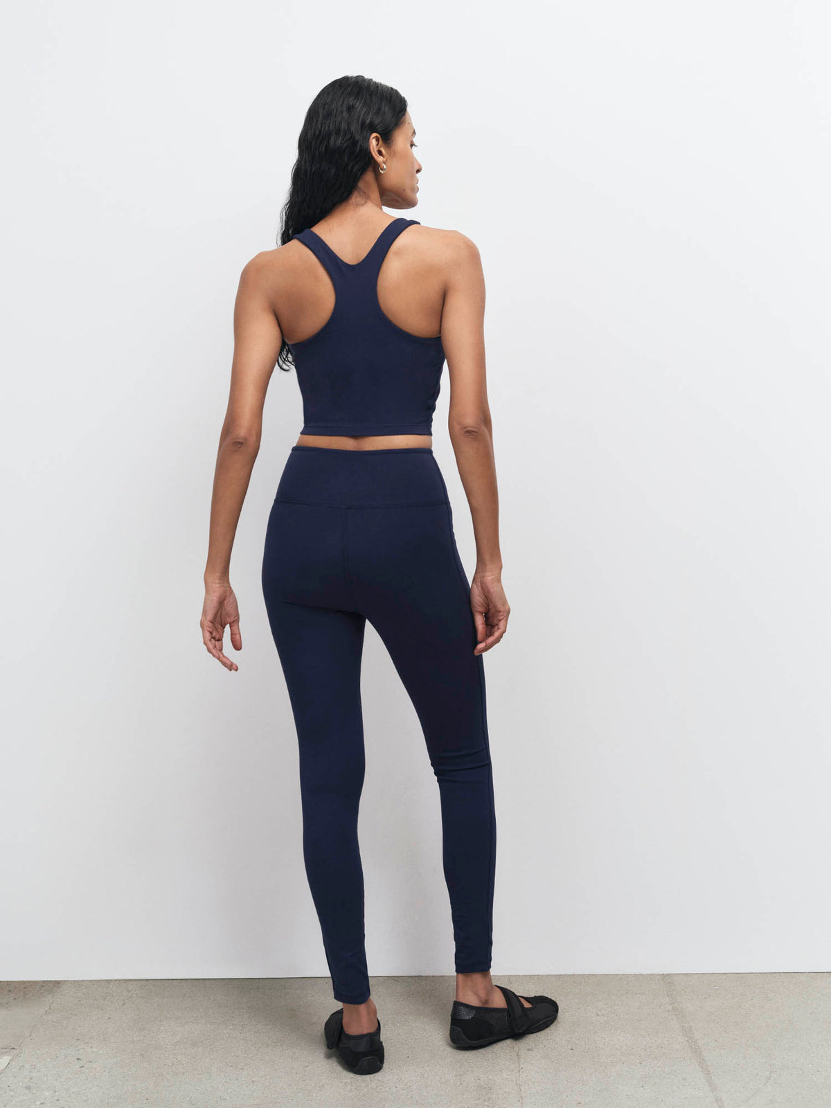 Back view of a midnight navy racerback organic sports bra and midi leggings – MATE the Label