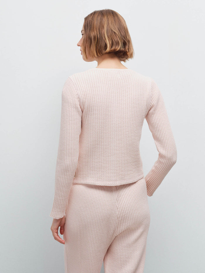 Woman wearing a pale pink waffle-knit cardigan and matching wide-leg pants, back view in studio