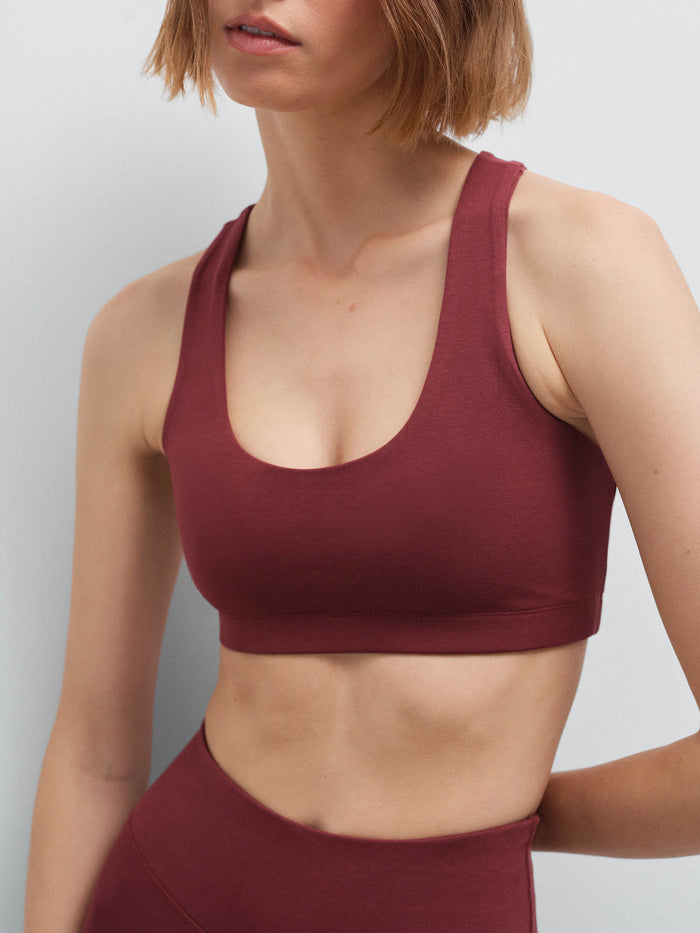 Close-up of a woman wearing a burgundy racerback sports bra and matching high-waist leggings
