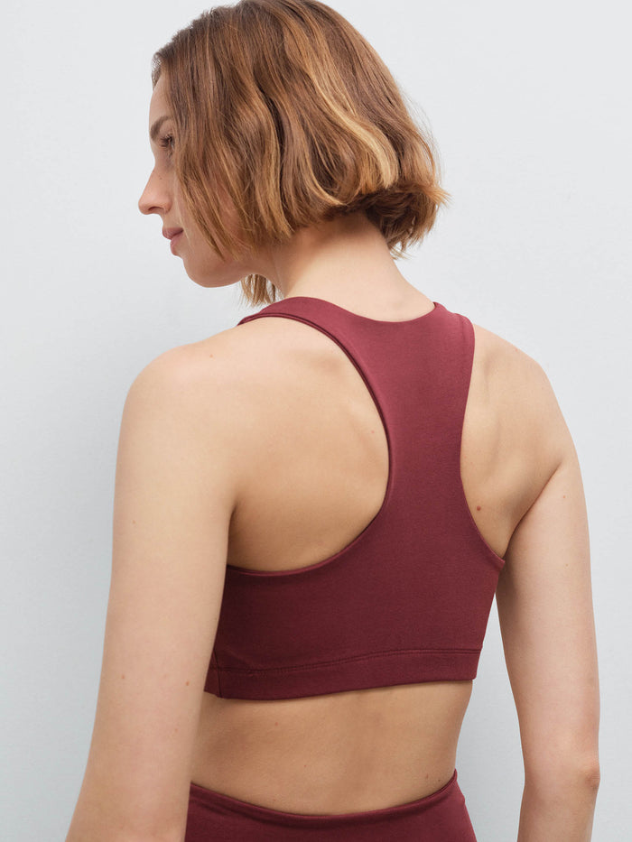 Close-up back view of a woman wearing a burgundy racerback sports bra