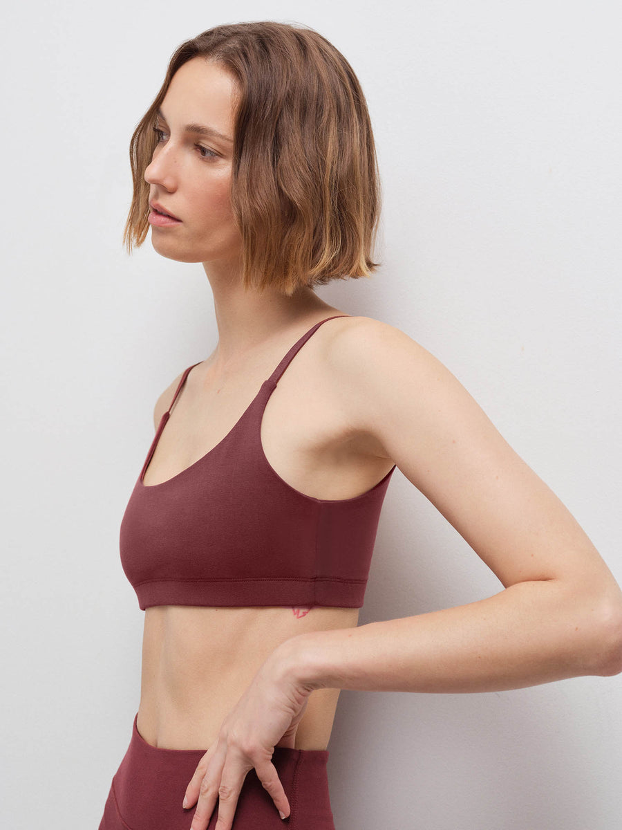 Close-up side profile of a woman wearing a burgundy scoop-neck bra