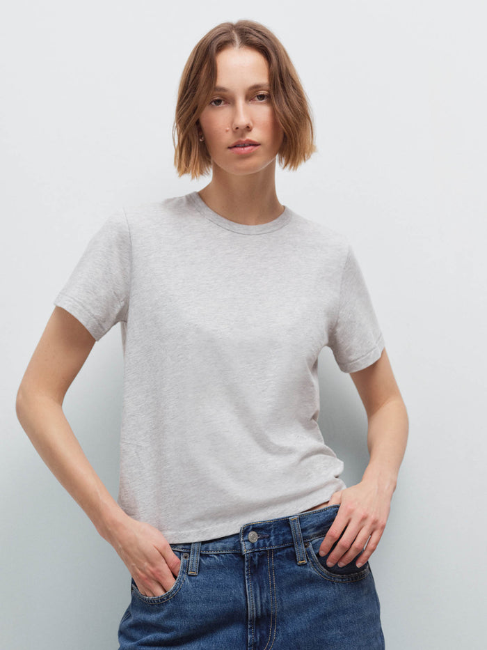 Woman wearing a heather grey crew-neck tee with dark denim jeans, front view in studio