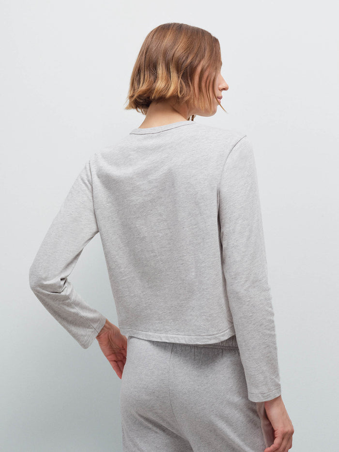 Woman wearing a heather grey long-sleeve cropped top, back view with matching sweatpants in studio