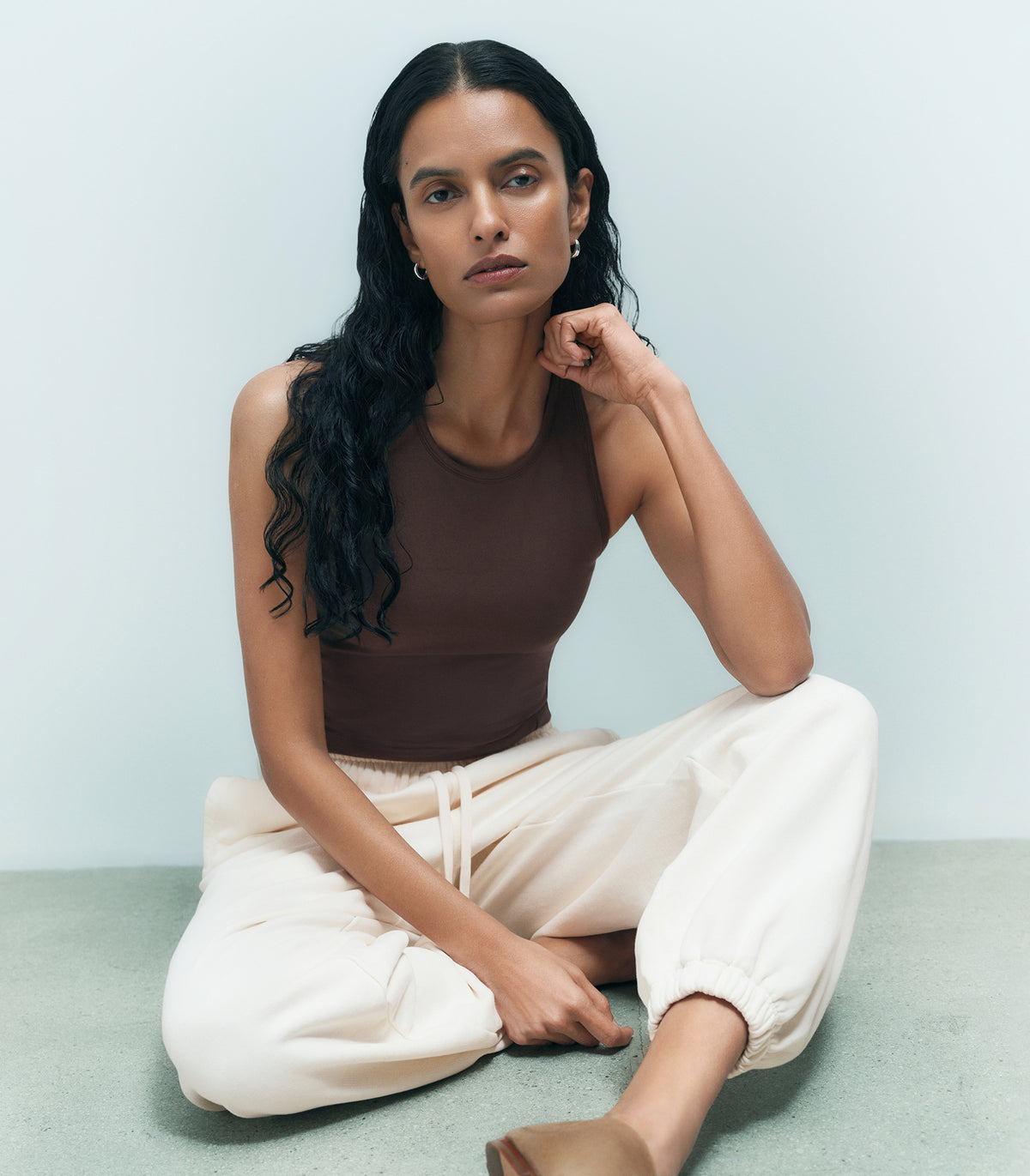 Woman in a brown organic tank and cream organic joggers seated on the floor – MATE the Label