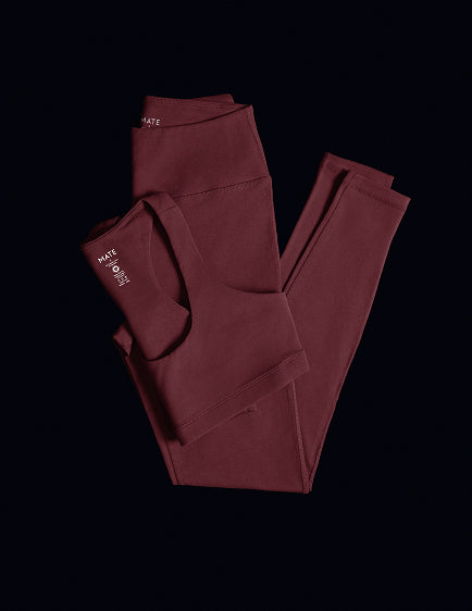 Burgundy organic stretch leggings and sports bra laid flat on black – MATE the Label