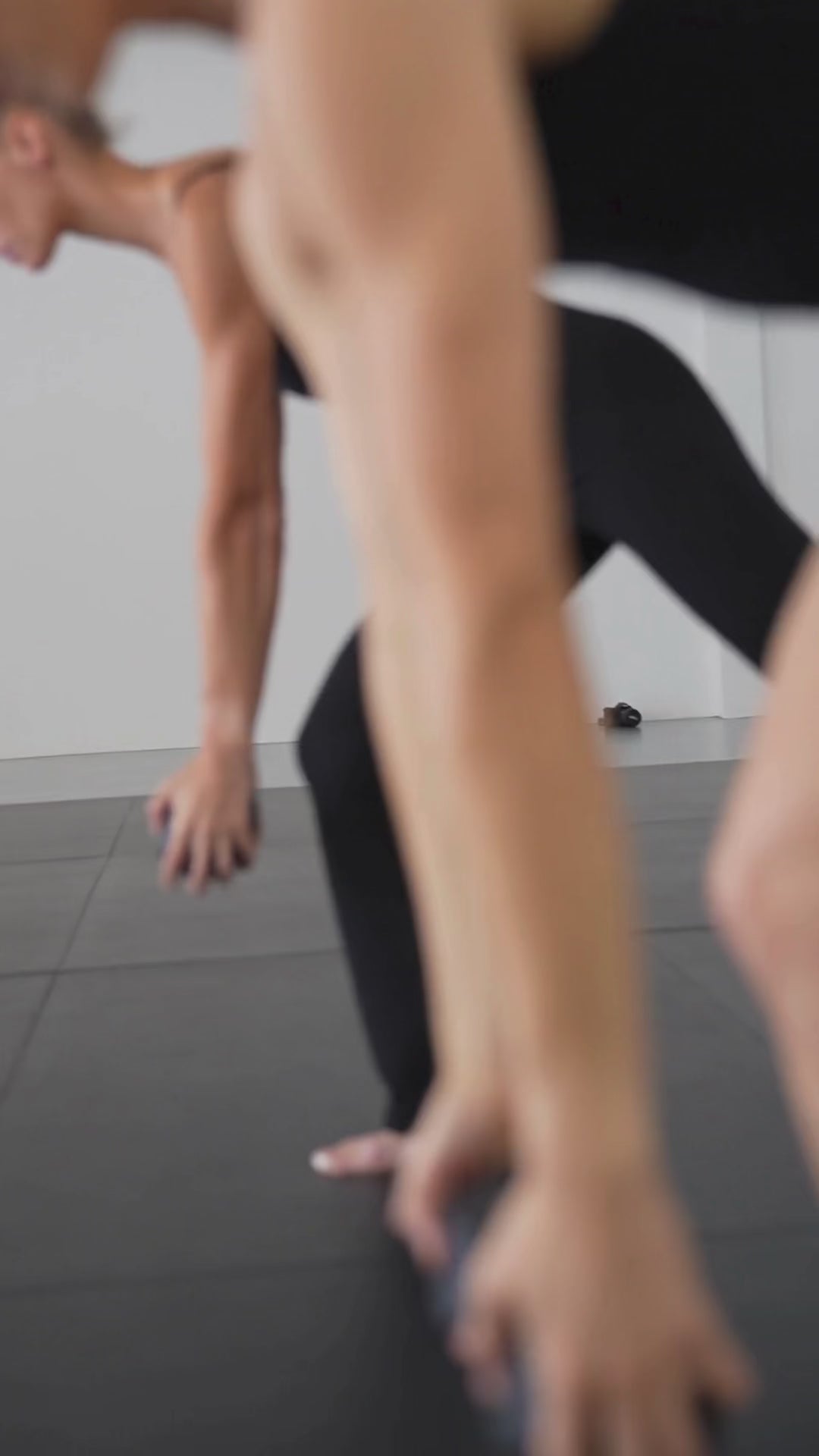 Video of a model in black leggings stretching on a studio floor